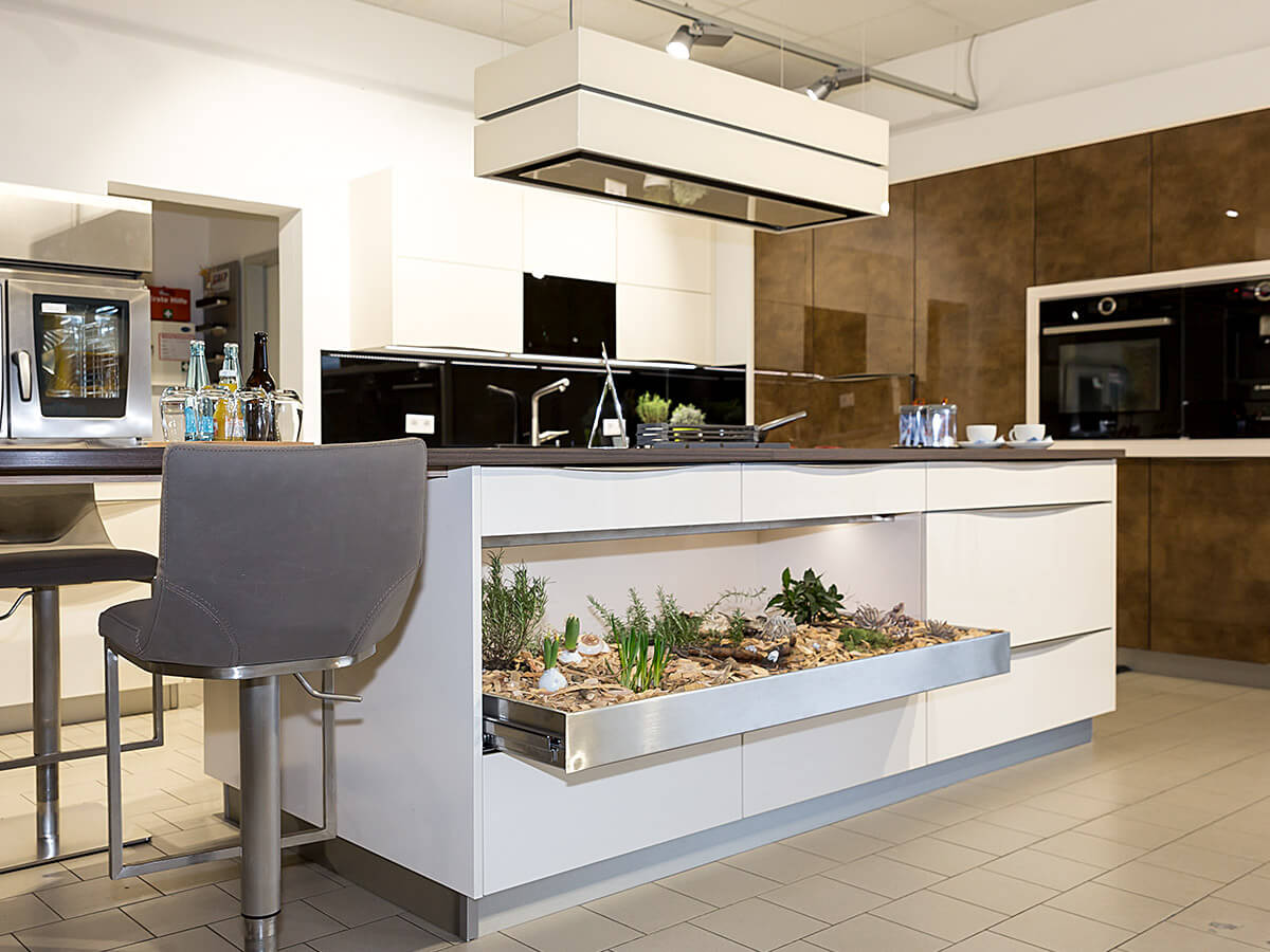Weisser Küchenstudio Showroom Kochinsel mit integrierter Begrünung